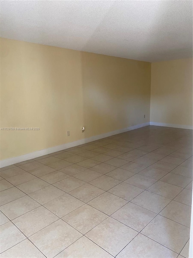 spare room with light tile patterned floors and a textured ceiling