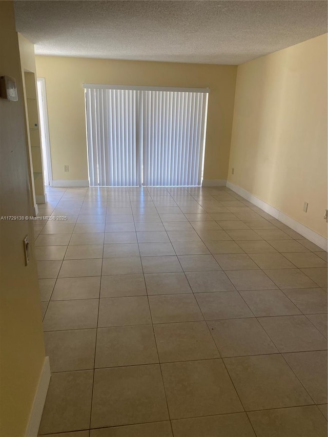 spare room featuring a textured ceiling and light tile patterned floors