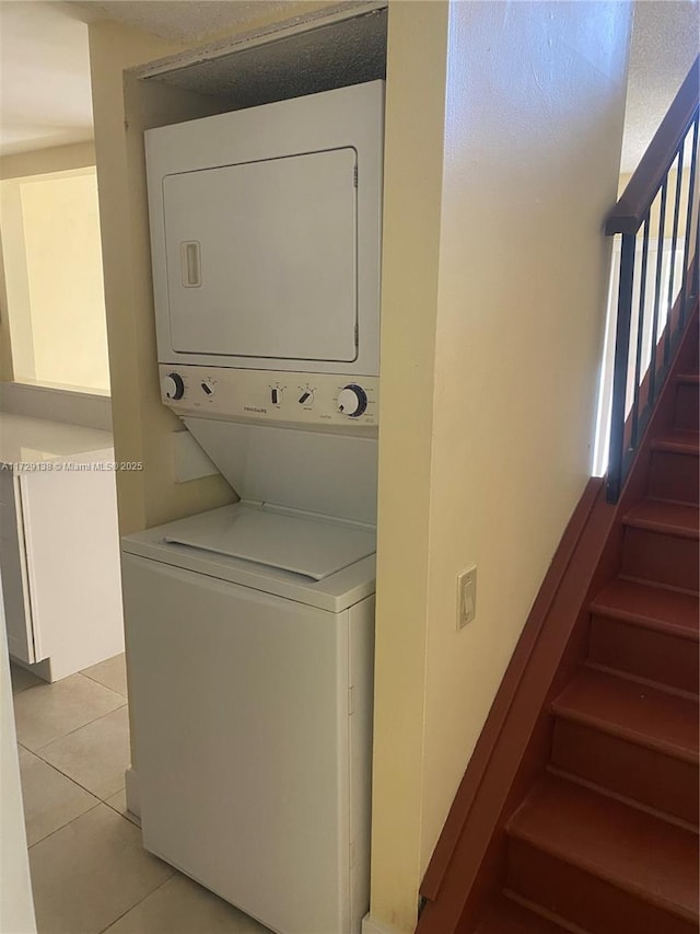 clothes washing area featuring stacked washer and clothes dryer and light tile patterned floors