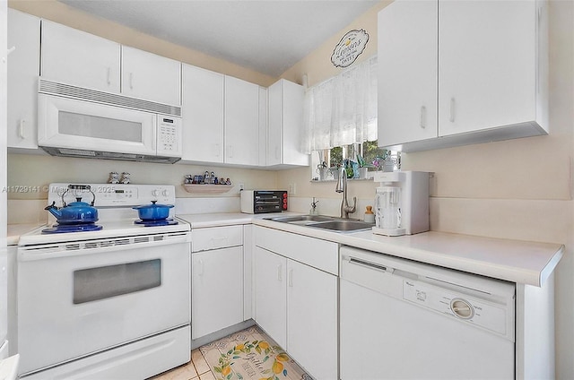 kitchen with white cabinets, light tile patterned floors, sink, and white appliances