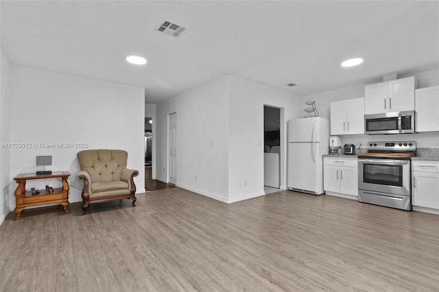 kitchen with white cabinetry, stainless steel appliances, washer / dryer, and light hardwood / wood-style floors