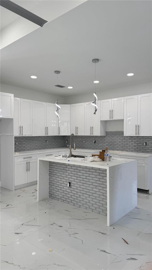 kitchen with a center island with sink, white cabinets, and hanging light fixtures