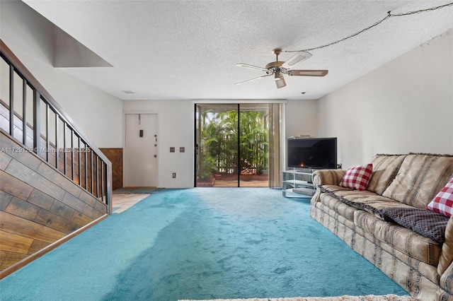 living room with ceiling fan, light colored carpet, a textured ceiling, and wood walls