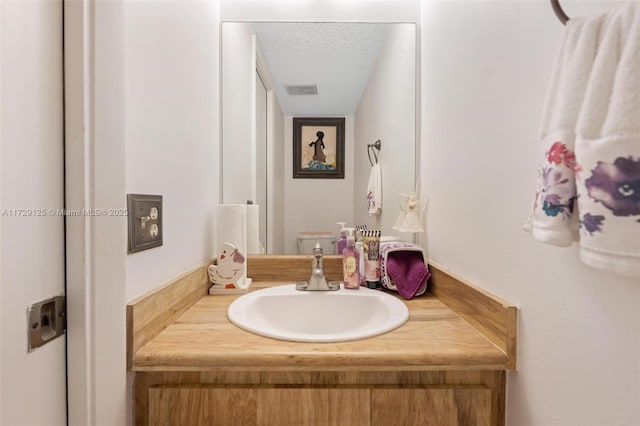 bathroom with toilet, vanity, and a textured ceiling