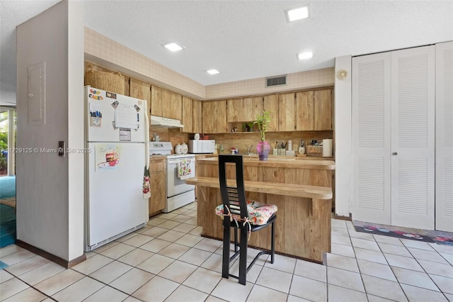 kitchen featuring white appliances, light tile patterned floors, and a textured ceiling