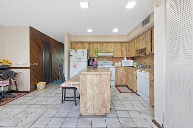 kitchen featuring light tile patterned floors, a center island, a breakfast bar, and white appliances