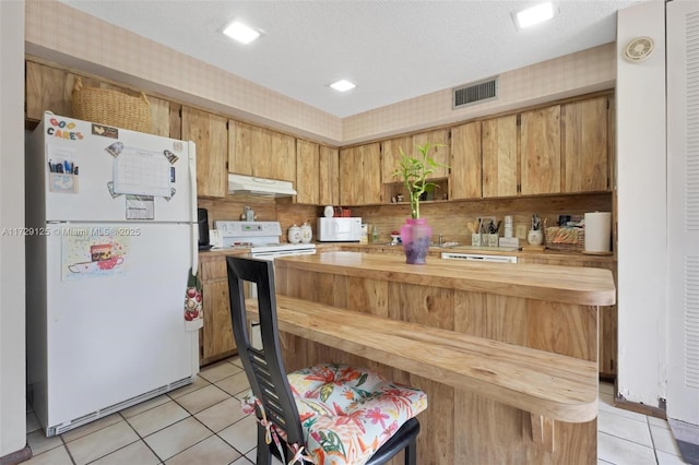 kitchen with kitchen peninsula, white appliances, a textured ceiling, light tile patterned floors, and wood counters