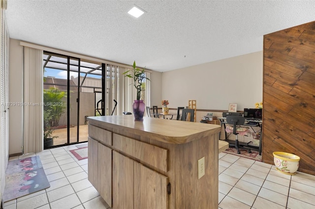 kitchen featuring light tile patterned floors, wooden walls, and a textured ceiling