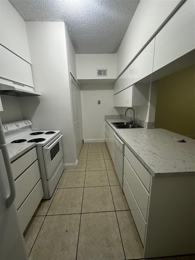 kitchen with light tile patterned floors, white cabinetry, white appliances, a textured ceiling, and sink