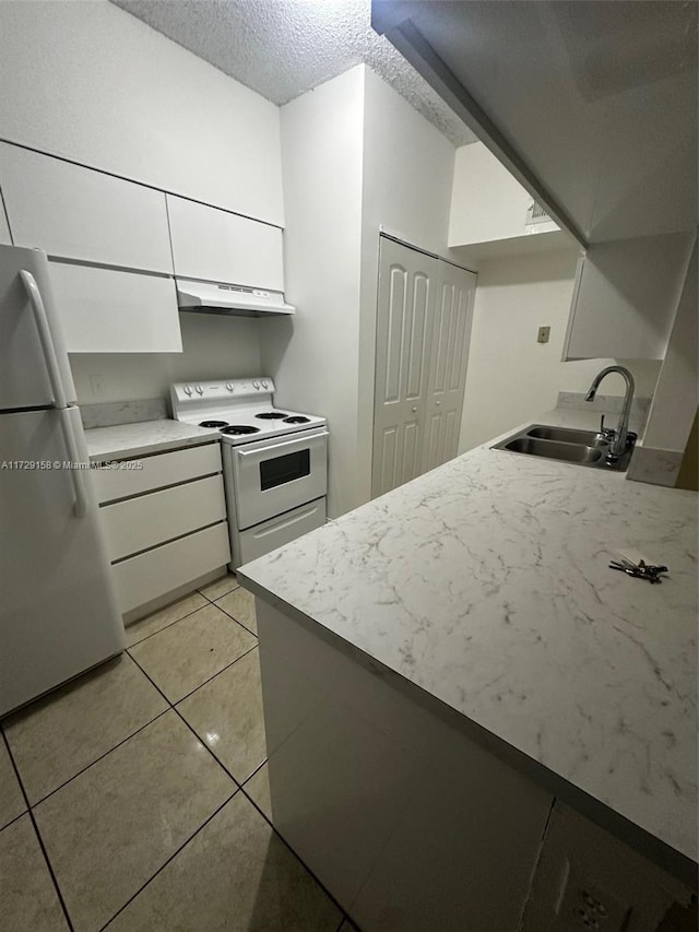 kitchen featuring sink, light tile patterned floors, white appliances, a textured ceiling, and white cabinets