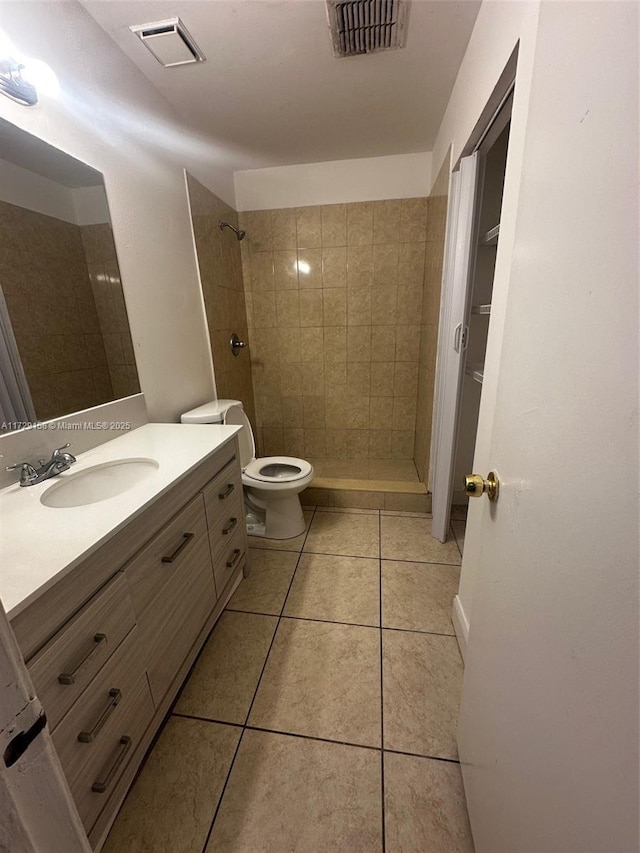 bathroom with toilet, tile patterned flooring, and tiled shower