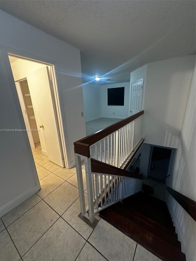 stairs featuring a textured ceiling and tile patterned flooring