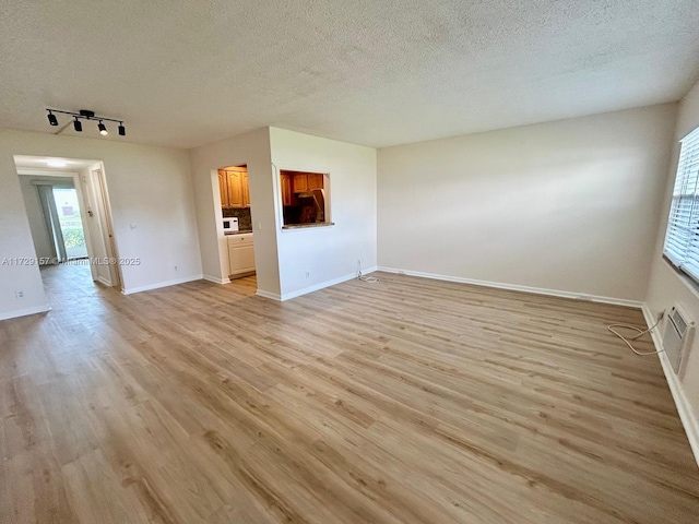 unfurnished living room featuring a textured ceiling, track lighting, and light wood-type flooring