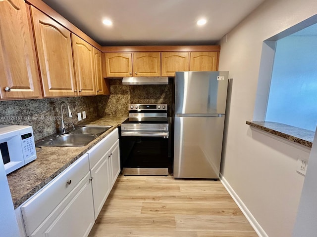 kitchen featuring tasteful backsplash, dark stone countertops, sink, light wood-type flooring, and stainless steel appliances