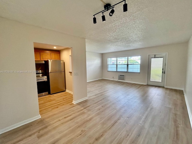 unfurnished living room featuring a textured ceiling, a wall mounted AC, and light hardwood / wood-style flooring