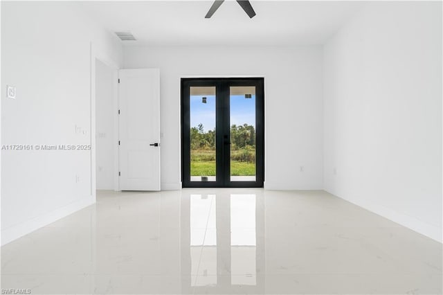 empty room featuring ceiling fan and french doors