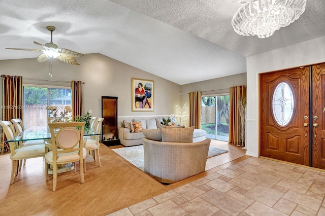 entryway featuring vaulted ceiling, ceiling fan with notable chandelier, and a textured ceiling