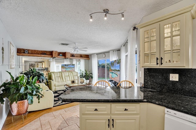 kitchen featuring decorative backsplash, kitchen peninsula, white dishwasher, and a textured ceiling