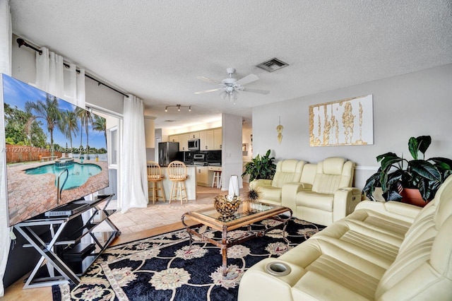 living room featuring ceiling fan and a textured ceiling