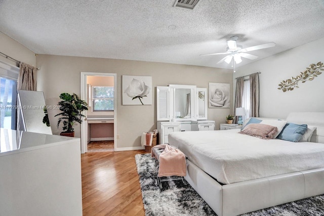 bedroom with a textured ceiling, light hardwood / wood-style flooring, and ceiling fan