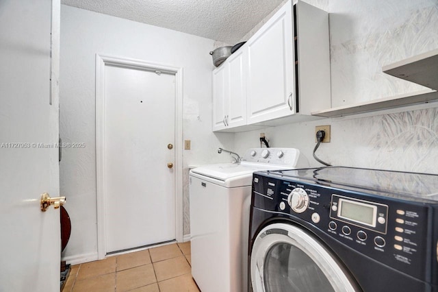 laundry room featuring a textured ceiling, separate washer and dryer, cabinets, and light tile patterned floors