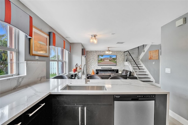 kitchen featuring stainless steel dishwasher, light stone countertops, sink, and tasteful backsplash