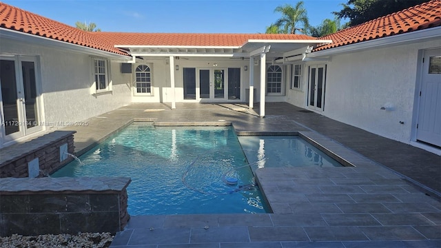 view of pool with french doors, pool water feature, and a patio