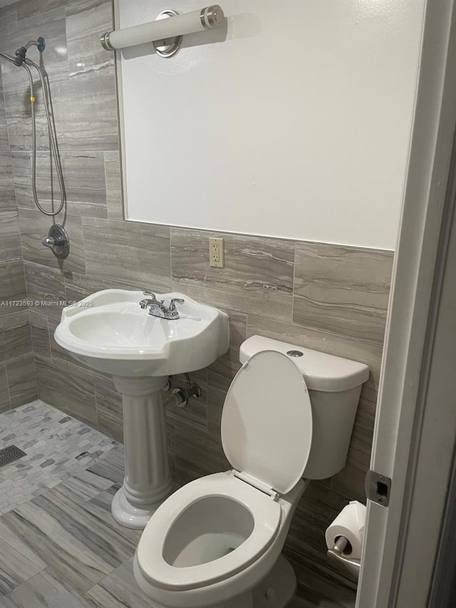 bathroom with toilet, tile walls, and a tile shower