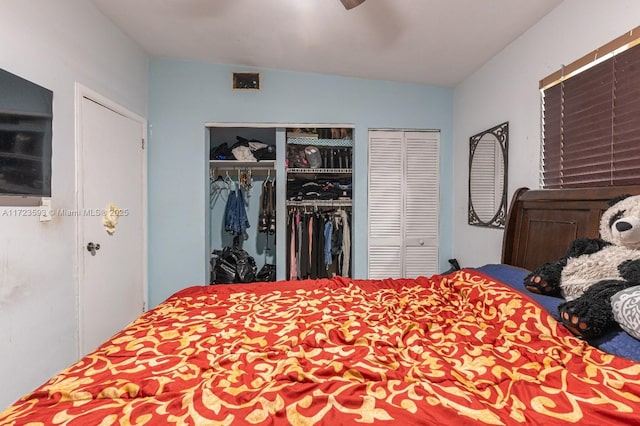 bedroom with ceiling fan, vaulted ceiling, and two closets