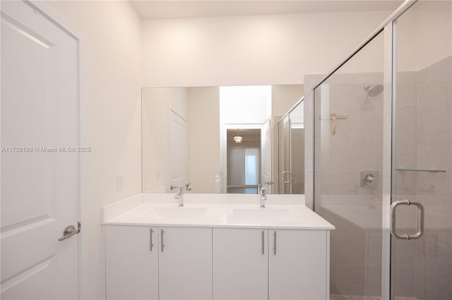 full bathroom featuring double vanity, a stall shower, and a sink