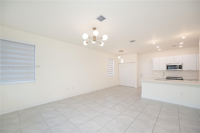 kitchen with decorative light fixtures, light countertops, stainless steel microwave, visible vents, and white cabinetry