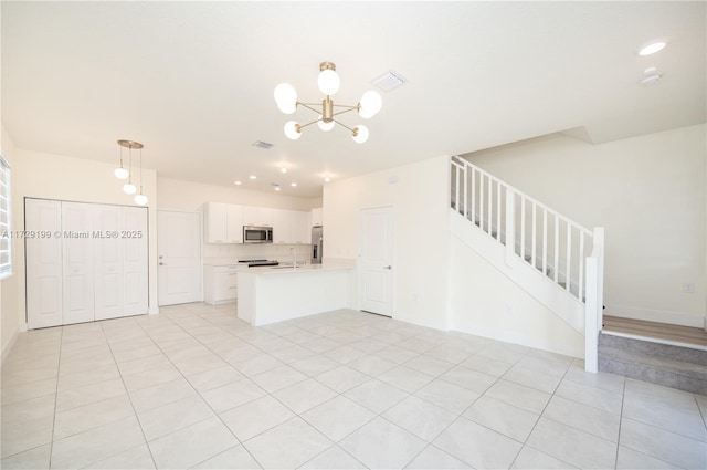 kitchen featuring open floor plan, stainless steel appliances, light countertops, white cabinetry, and a sink