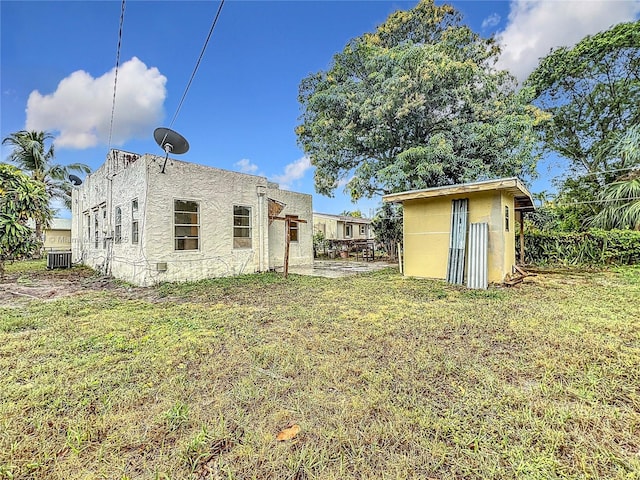 exterior space with a yard, cooling unit, and a storage shed