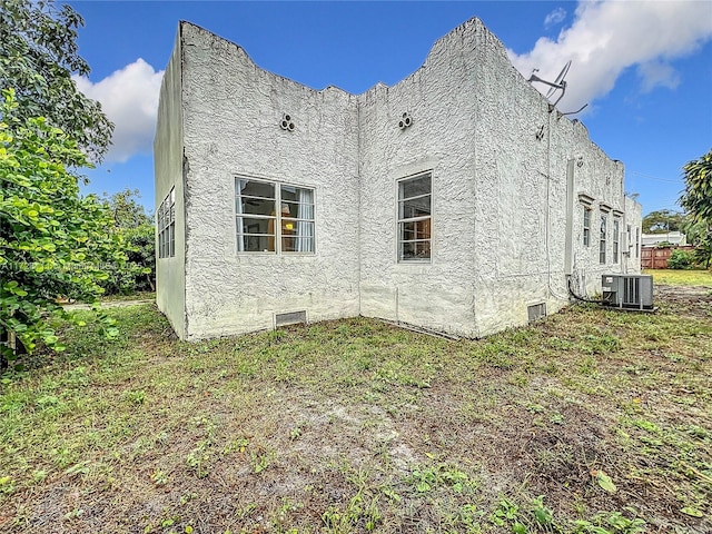 view of property exterior featuring central AC unit and a lawn