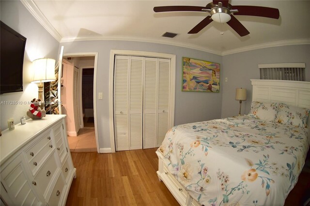 bedroom featuring light hardwood / wood-style floors, a closet, ceiling fan, and ornamental molding