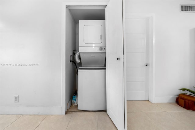 washroom with stacked washing maching and dryer and light tile patterned floors