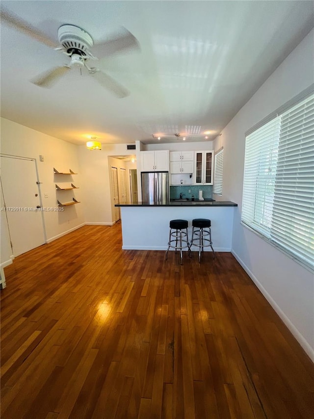 1523 W Ave Unit 101, Miami Beach, FL 33139 - kitchen with freestanding refrigerator, dark countertops, a peninsula, white cabinetry, and glass insert cabinets