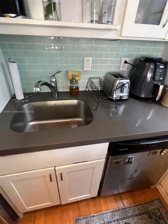 kitchen featuring light hardwood / wood-style floors, white cabinets, tasteful backsplash, and sink