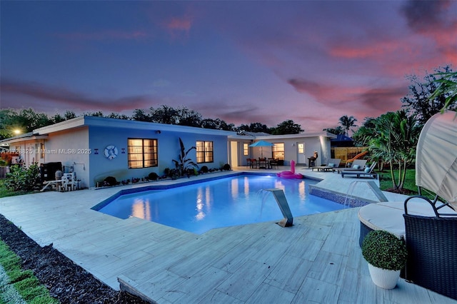 pool at dusk featuring a patio area