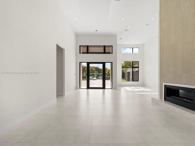 interior space featuring light tile patterned floors, a fireplace, and a high ceiling