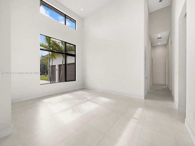 tiled spare room with a high ceiling