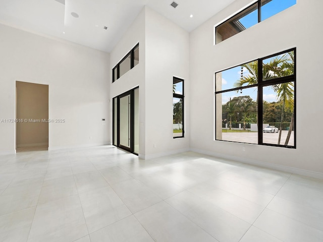 tiled spare room with a high ceiling