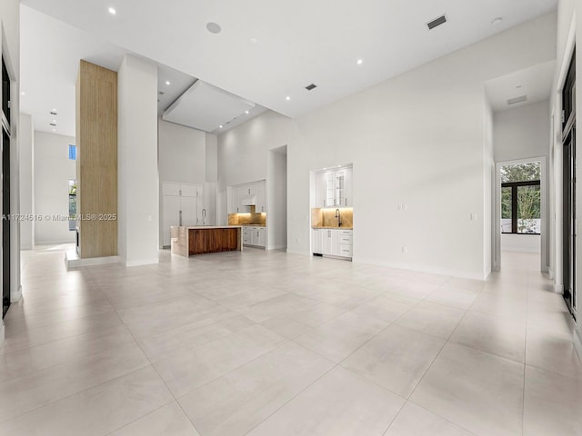 tiled spare room featuring a towering ceiling