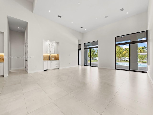 tiled empty room featuring a high ceiling and sink