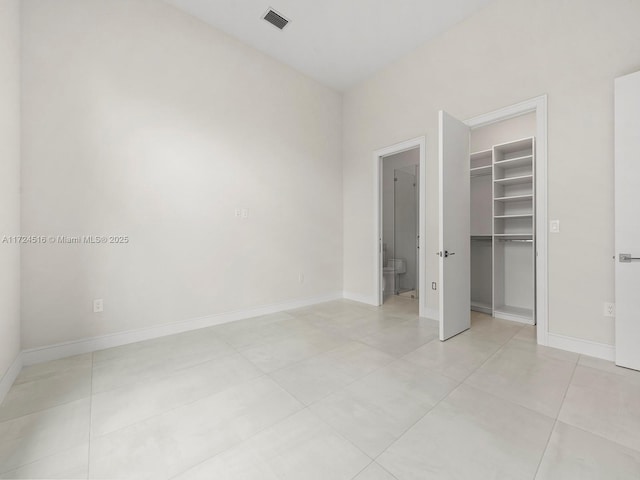 unfurnished bedroom with light tile patterned floors, a closet, and a walk in closet