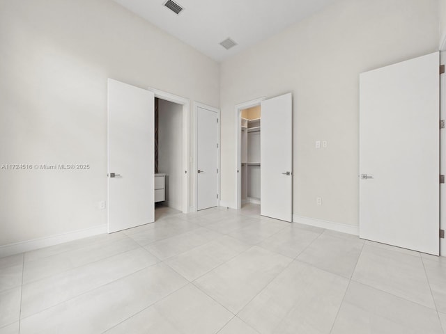 unfurnished bedroom with light tile patterned floors, a closet, and a walk in closet