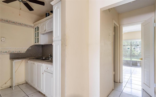 kitchen with sink, light tile patterned floors, ceiling fan, decorative backsplash, and white cabinets