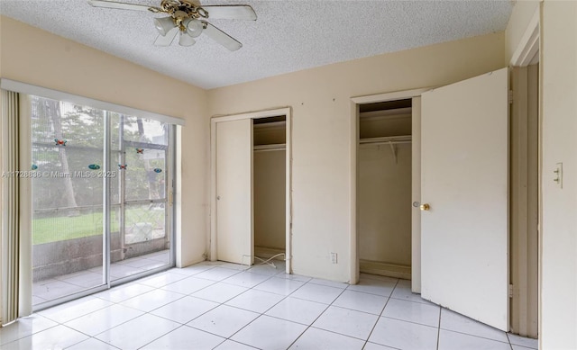 unfurnished bedroom featuring access to outside, light tile patterned floors, ceiling fan, multiple closets, and a textured ceiling