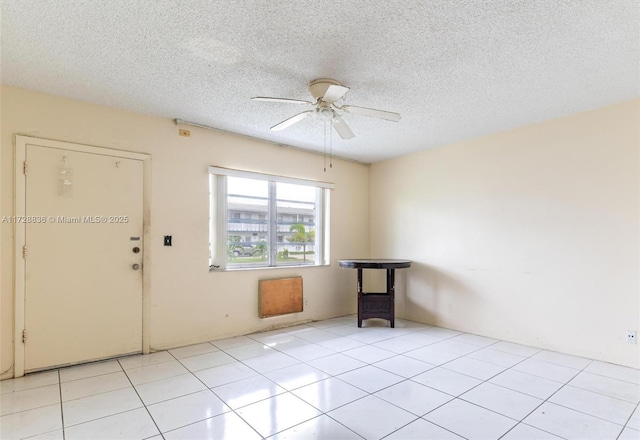 tiled empty room featuring ceiling fan and a textured ceiling