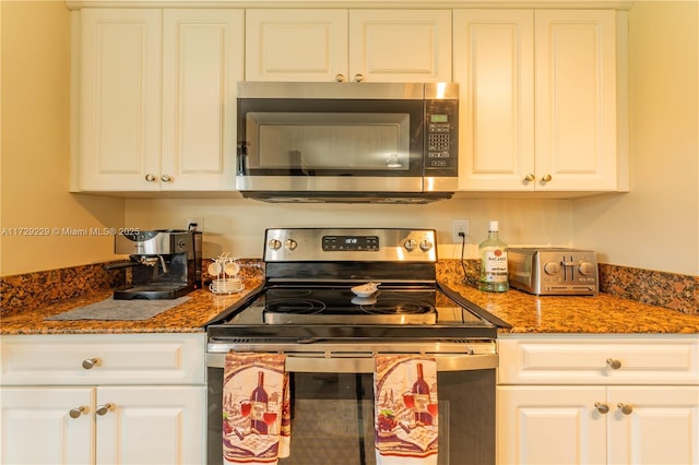 kitchen with white cabinets, stainless steel appliances, and dark stone counters